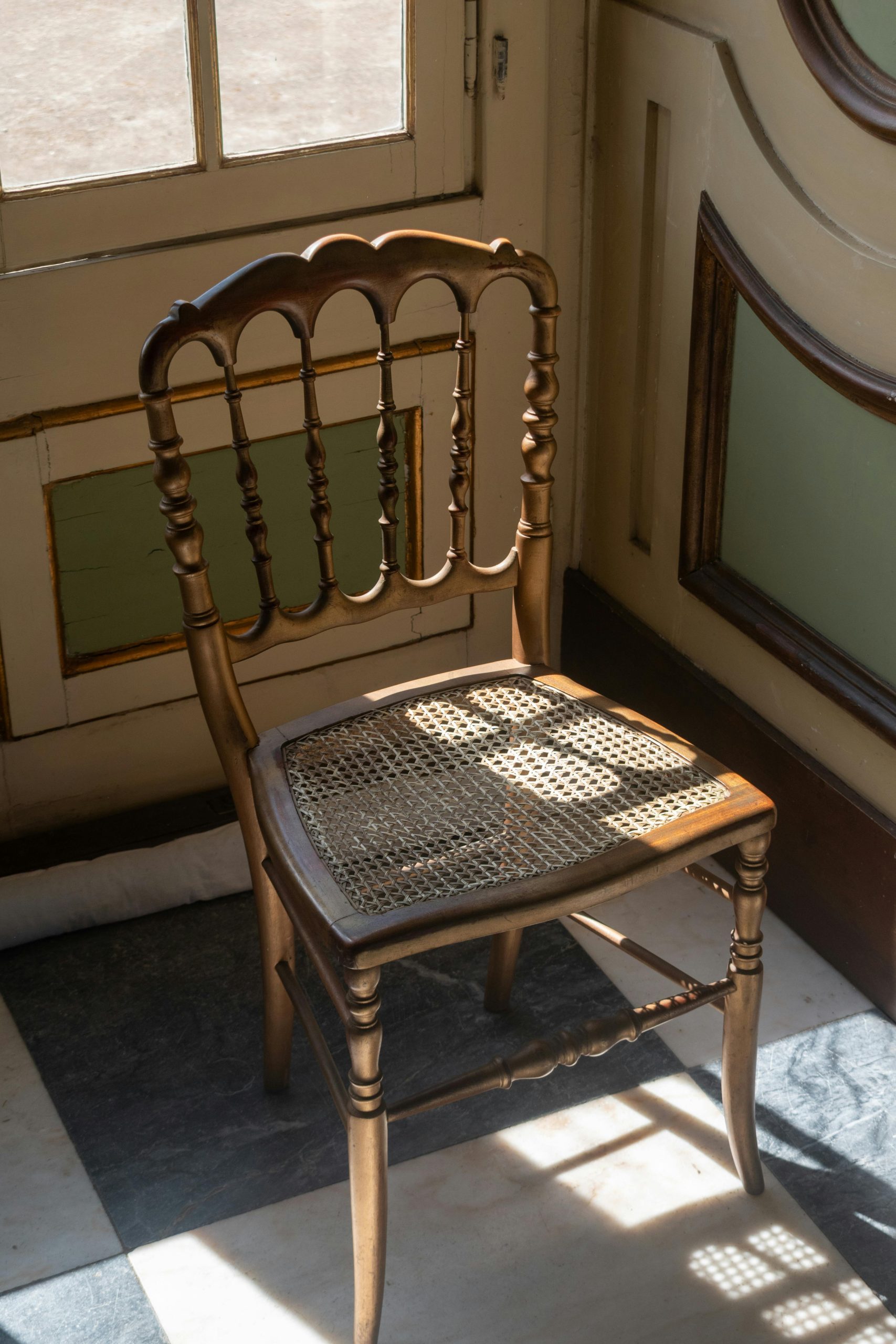 A classic wooden chair in a sunlit corner, capturing the elegance of vintage design.